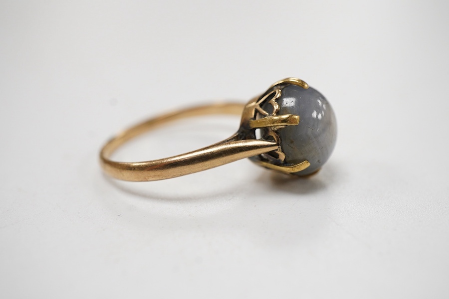 A yellow metal and single stone claw set star sapphire ring, size P, the stone approx. 9mm in diameter.